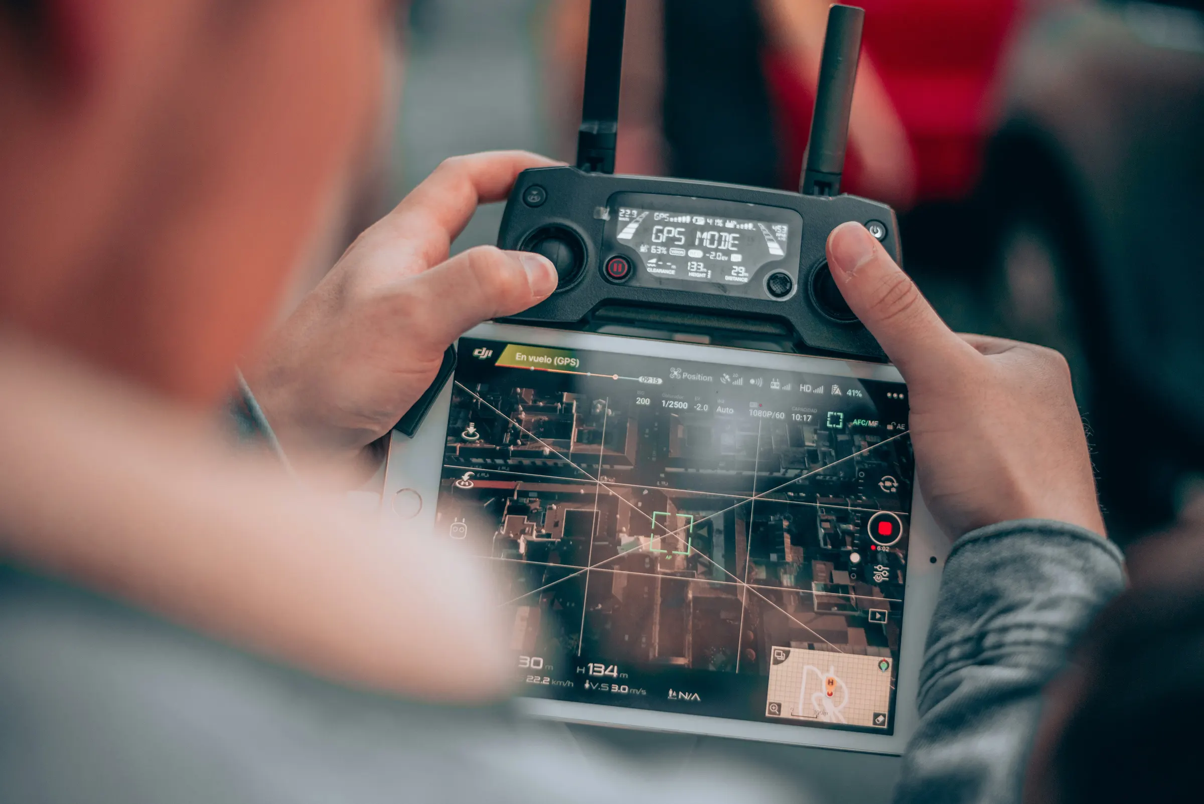 Télépilote aux commandes d'un drone, la vue aérienne d'un quartier s'affichant sur l'écran de la radiocommande